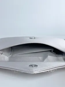 Nahaufnahme der Innenausstattung der silbernen Satin-Abendtasche mit Magnetverschluss.