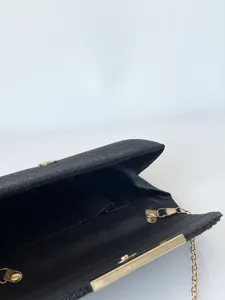 Detailaufnahme der schwarzen Glitzer-Abendtasche mit goldenem Metallrahmen und Kette.