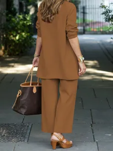 Outdoor street lifestyle detail showing a casual brown women suit jacket and matching trousers.