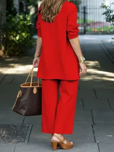 Detail view of stylish red long-sleeve top and wide-leg trousers set worn outdoors.