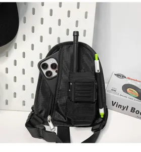 Dettaglio borsa pettorale tattica nera con tasca per telefono e custodia per walkie-talkie.