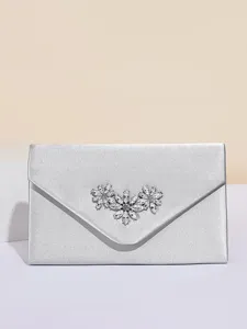 Edles Detail der silbernen Satintasche mit einem funkelnden Strassblumen-Zierornament.