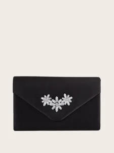 Detailaufnahme der schwarzen Satin Abendtasche mit funkelnder Kristallblumen Brosche.