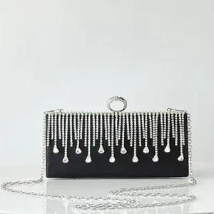 Close-up of black evening clutch bag with sparkling rhinestone fringe and metal chain.