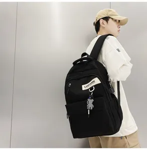 Vue détaillée du sac à dos noir décontracté avec patch logo et charmant pendentif d'ours.