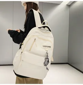 Vue détaillée du grand sac à dos blanc en toile avec pendentif ours mignon pour l'école.