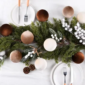 Bolas de Navidad flocadas de terciopelo detalle de mesa con ramas de pino y bayas blancas.