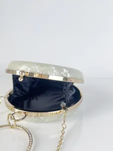 Elegante runde Hartschalen-Abendtasche mit goldenem Metallrahmen und Strass-Griff.