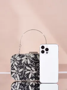 Detailaufnahme einer schwarzen Perlen Abendtasche mit silbernem Metallgriff und Handy.