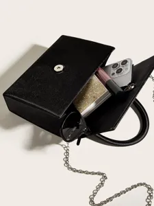 Detailansicht einer schwarzen Satin-Abendtasche mit Kette und stilvollen Accessoires.