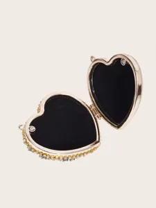 Nahaufnahme einer herzförmigen Mini-Strass-Tasche mit goldenem Metallrahmen und Samt.