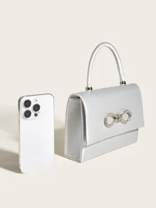 Silberne Satin Abendtasche Detailansicht mit Strass Schleife und praktischem Handy Grössenvergleich