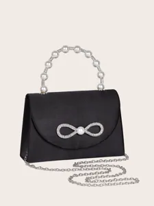 Detailaufnahme der schwarzen Abendtasche mit Perlenhenkel, Glitzer-Schleife und Kette.