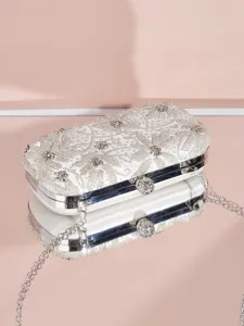 Nahaufnahme der silbernen Perlen-Abendtasche mit Strassverschluss und glänzender Spiegelung.