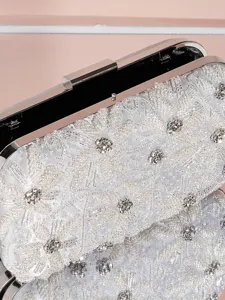 Exquisites Detail einer silbernen Perlen-Abendtasche mit feiner Stickerei und Metallrahmen.