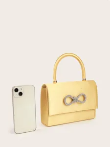 Detailansicht der eleganten gelben Satin Abendtasche mit funkelnder Strass Schleife.