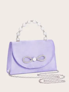 Exquisites Strass-Schleifen- und Perlenhenkel-Detail an einer eleganten Satin-Abendtasche.