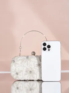 Detailansicht der wunderschönen weißen Perlen-Abendtasche mit glänzendem Metallgriff.