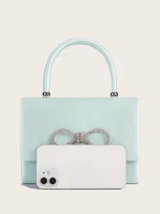 Hellblaue Satin Abendhandtasche Detail mit funkelnder Strass Schleife und glatter Griff Textur.