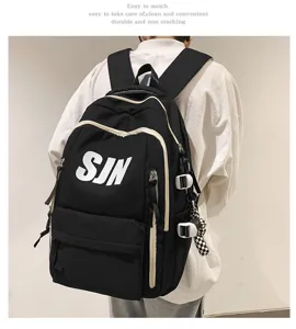 Detail view of black canvas school backpack with white letters and side accessories.