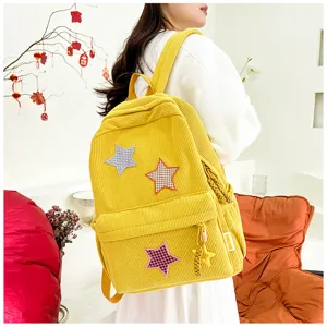 Detail view of yellow corduroy small backpack for cute girls with star patches and charms.