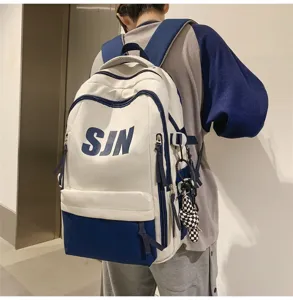 Detail view of large capacity color block backpack with side straps and cute bear pendant.