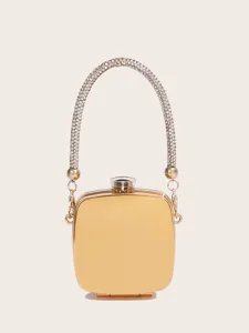 Detailansicht der luxuriösen goldenen Mini-Clutch mit funkelndem Strassstein-Tragegriff.