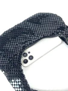 Detailaufnahme einer schwarzen Metallic-Netz-Tasche mit Smartphone als Größenvergleich.