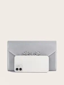 Detailansicht der eleganten silbernen Satin-Abendtasche mit funkelndem Kristallblumendekor.