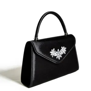 Detailansicht der schwarzen Satin-Abendtasche mit funkelnden Kristallblumen und Henkel.