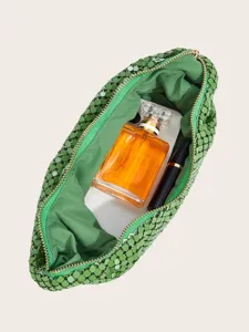 Detailansicht des Inneren einer gruenen Pailletten-Netz-Abendtasche mit Accessoires.
