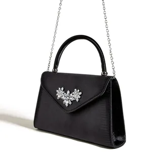 Schwarze Abendtasche aus Satin Detail mit funkelnder Kristallblumenbrosche und Silberkette.
