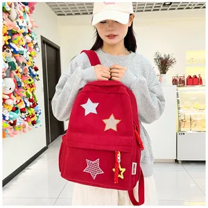Red corduroy backpack detail featuring star patches and cute pendant, casual daily use.