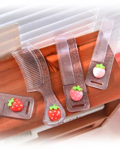 Close-up van doorzichtige glanzende haarkammen met schattige 3D cartoon aardbeibedeltjes.