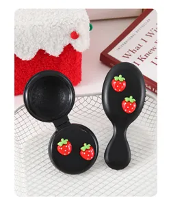 Close-up detail of cute black foldable air cushion massage hair comb decorated with 3D strawberry.