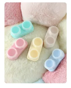 Gros plan de boîtiers de lentilles de contact colorés en teintes macaron sur fausse fourrure.