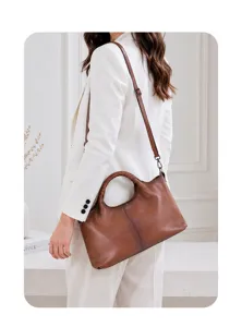 Detail view of a vintage brown genuine leather tote bag with ring handle and shoulder strap.