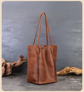 Dettaglio di una borsa tote vintage in vera pelle marrone con manici lunghi e texture.