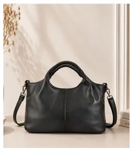 Black genuine leather handbag detail, soft texture, top handle and strap design, elegant look.