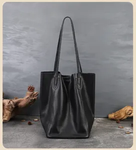 Dettaglio ravvicinato di borsa shopper in pelle nera con trama fine e manici robusti.
