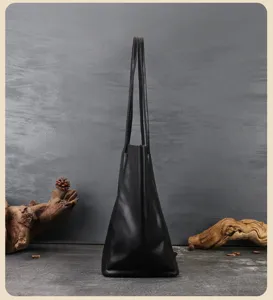 Vista dettagliata della borsa tote in pelle nera, design verticale con lunghi manici.