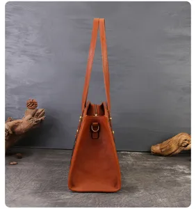 Elegant brown leather shoulder bag with spacious design and classic monogram pattern side panels.