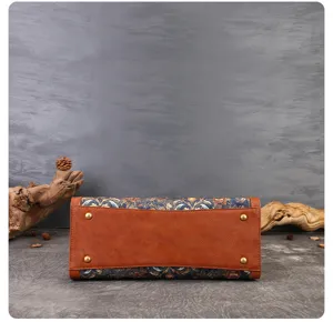 Vintage embroidered boston bag bottom detail view with brown leather and metal feet.