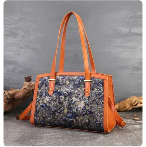 Detailed view of womens floral fabric shoulder bag with orange leather trim and gold hardware.