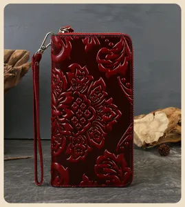 Red embossed leather women wallet detail view, vintage cowhide long clutch with wrist strap.