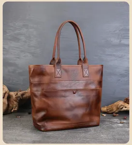 Detailed view of vintage brown leather tote bag, featuring sturdy dual handles and rustic wooden props.