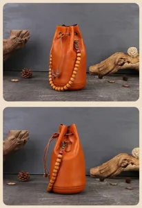 Handmade vegetable-tanned leather bucket bag with wooden bead handle and drawstring closure.