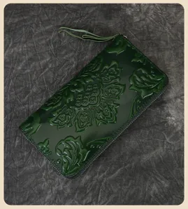 Detailed shot of dark green embossed leather wallet with floral pattern and zipper closure.