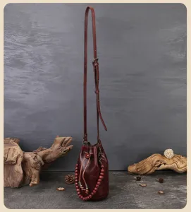 Detail view of vintage genuine leather bucket bag with drawstring and wooden bead handle.