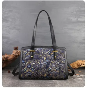 Exquisite embroidered shoulder bag detail, premium blue floral fabric and black leather handles.